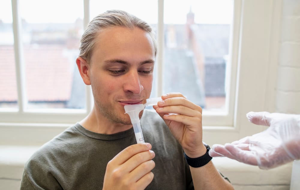 A man completes an at-home saliva collection kit for genetic testing.