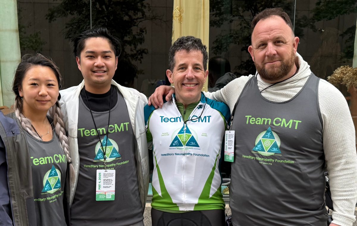 Four Team CMT riders in cycling jerseys and team shirts standing together with their arms around each other before a ride.