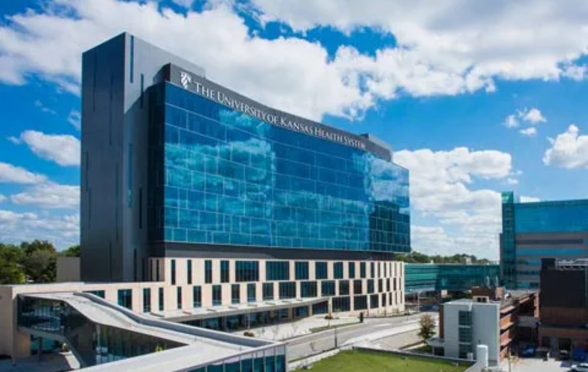 The glass and steel front of the University of Kansas Health System building under a blue sky.