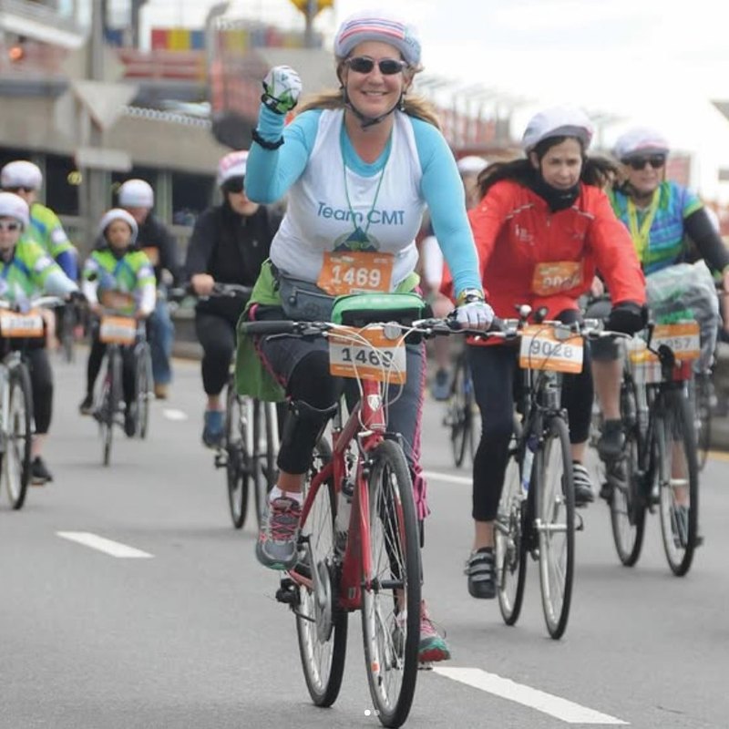 A Team CMT cyclist raising a hand in the middle of a pack of riders.