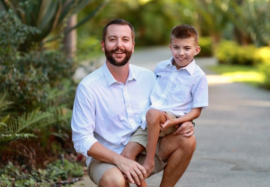 Jaxson and his father kneeling together outdoors, both smiling.
