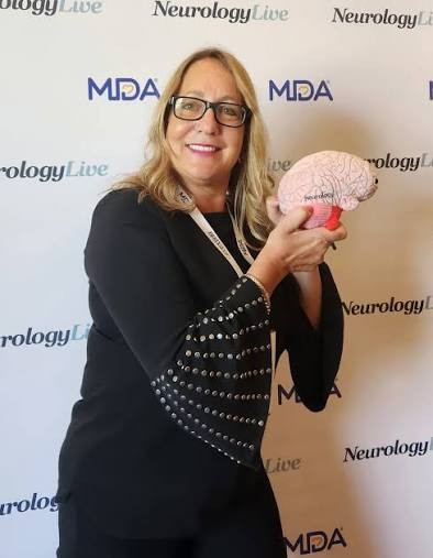 Allison Moore at a NeurologyLive and MDA event, holding a brain model.