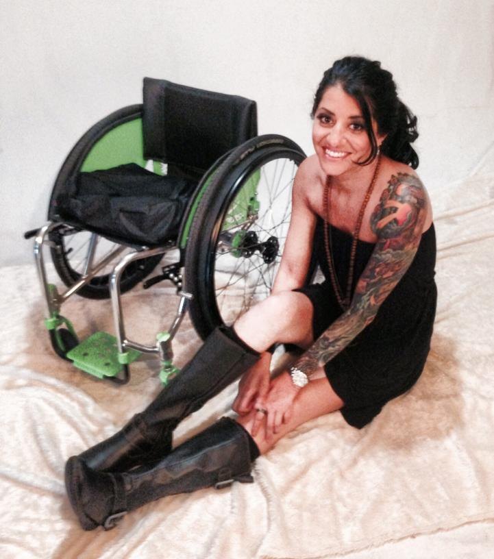 Bernadette smiling, seated on the floor beside her wheelchair.