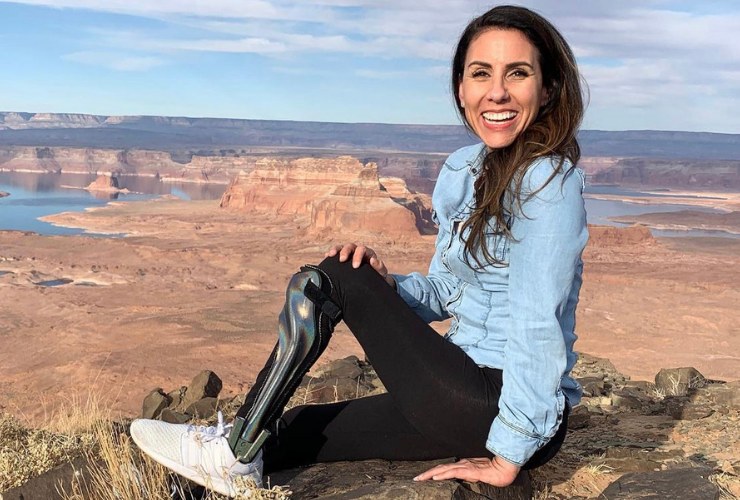 Estela Lugo sitting on rocks at a canyon overlook, wearing an ankle-foot brace.