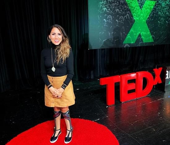 Estela Lugo on a TEDx stage, wearing her decorated ankle-foot braces.