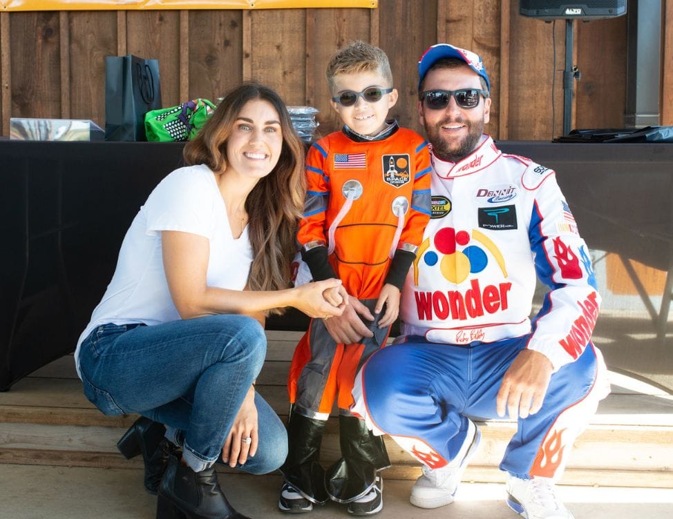 Jaxson in a racing suit meeting a race car driver at a fundraiser.