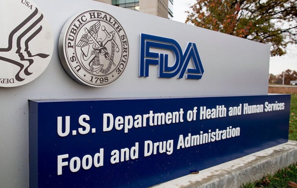 The sign outside the U.S. Food and Drug Administration campus, reading U.S. Department of Health and Human Services, Food and Drug Administration, next to an FDA building.