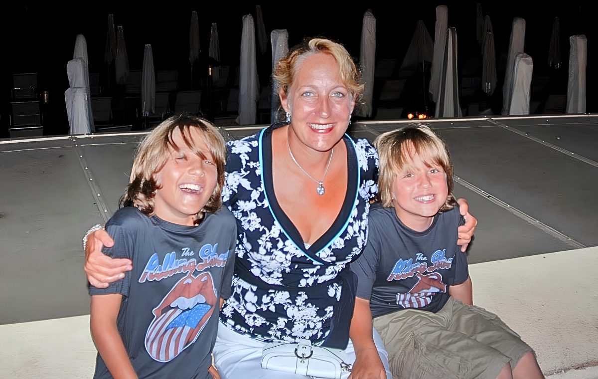 A smiling mother with her arms around her two young sons at an evening HNF community gathering.