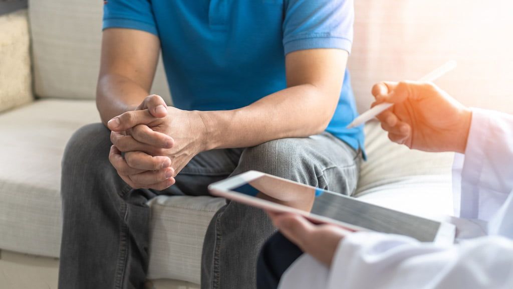 A person marking items on a printed health checklist before a medical appointment.