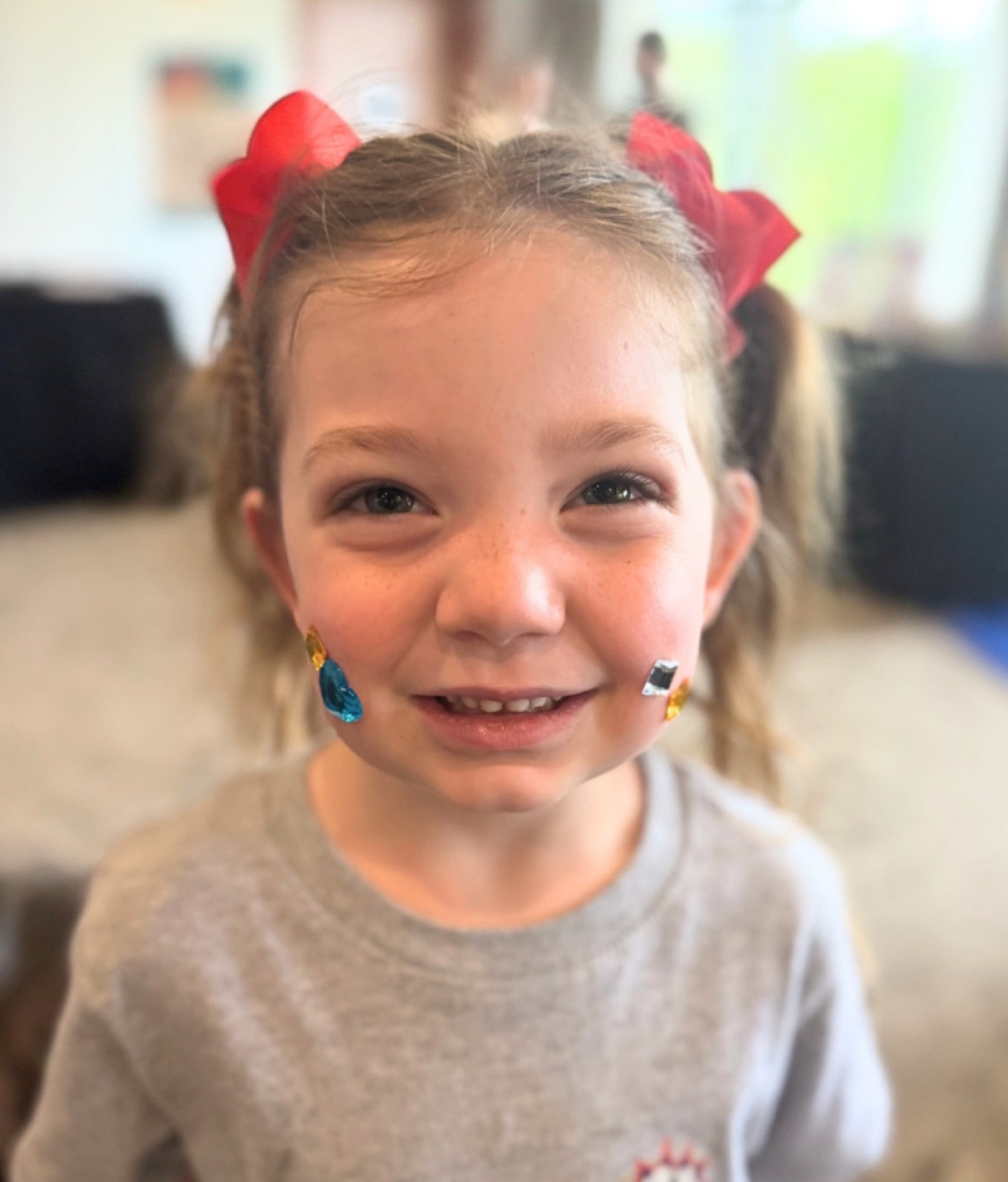 A young girl with red bows in her hair smiling at the camera.