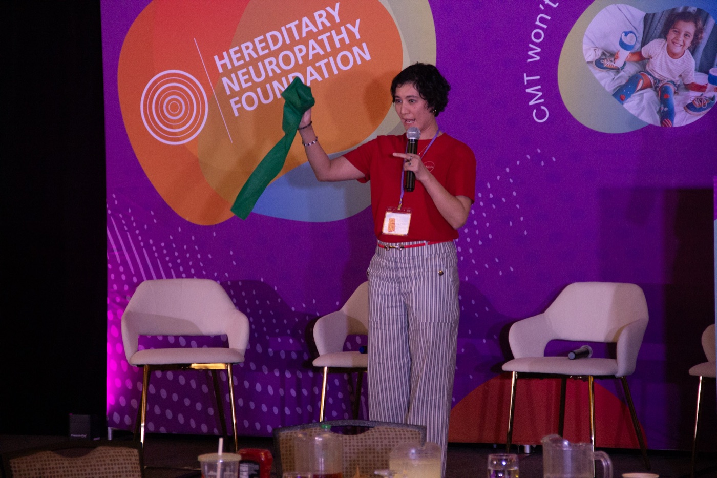 A presenter on the summit stage stretching a green resistance band during a demonstration.