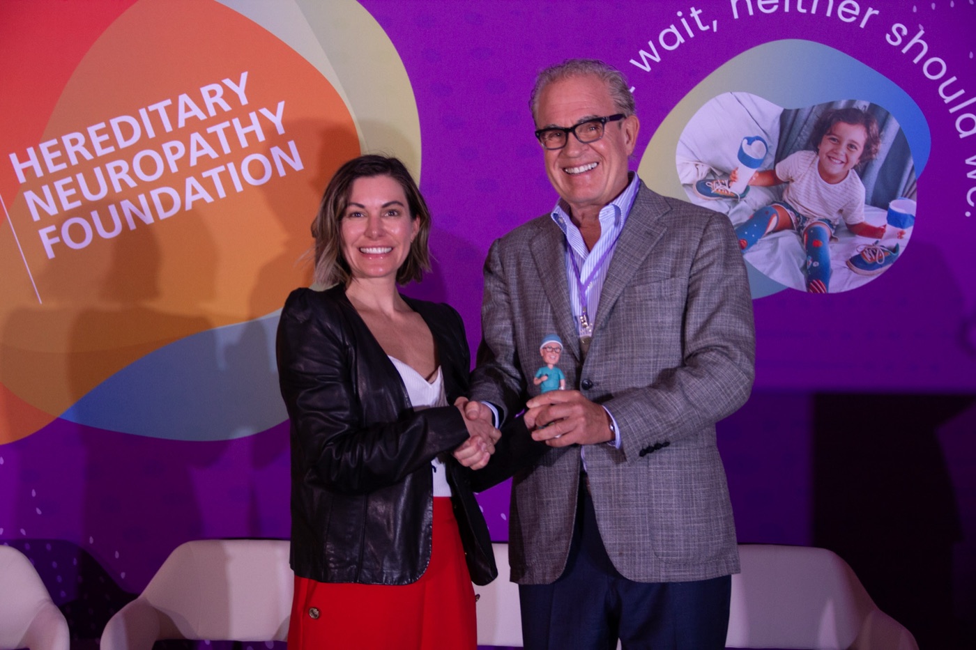 An award recipient in a suit accepting recognition on the summit stage.