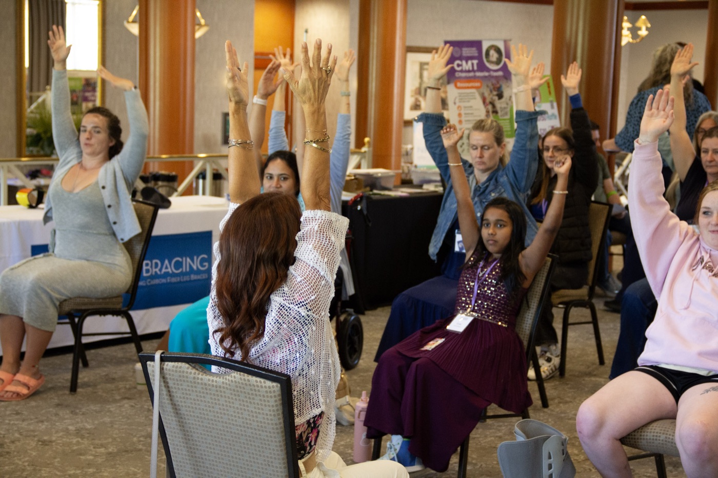 A roomful of attendees raising their hands during an interactive summit session.